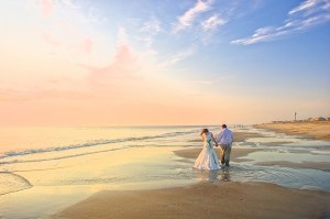 Newly-Married-Couple-Walking-Along-Beach